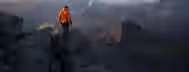 Ascending the Summit of Self-Discovery An individual in an orange jacket scales a rocky mountain, symbolizing the challenging yet rewarding journey to self-improvement and leadership.