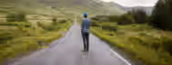 Journey of Growth on Open Roads A lone traveler stands on an endless road through lush valleys, symbolizing the journey of an emerging leader towards self-improvement.