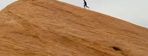 Climbing the Summit of Self-Discovery A lone climber scaling a steep, barren slope, symbolizing the challenging journey towards leadership and self-improvement.