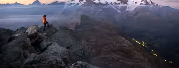 Summiting Challenges: A Leader's Ascent to Growth A climber gazes at a distant, snow-capped peak, symbolizing the journey and self-discovery of an emerging leader striving for greatness.
