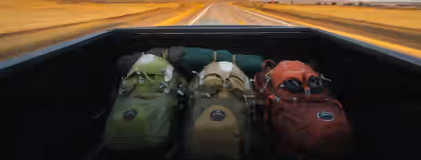 Journey of a Leader: The Road Ahead Backpacks in a truck bed, racing toward the horizon, symbolize the journey and growth of an emerging leader.