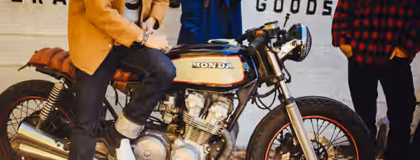 Revving Up to Leadership: The Road to Self-Discovery A young leader prepares for a journey, confidently standing by a classic motorcycle, symbolizing the drive for self-improvement.