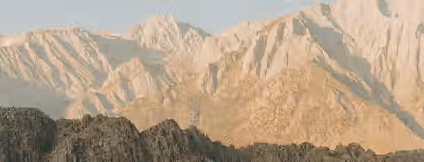 Scaling Heights: A Leader's Path to Growth A golden sun illuminates rugged mountains, symbolizing a leader's arduous journey toward self-improvement and ultimate achievement.