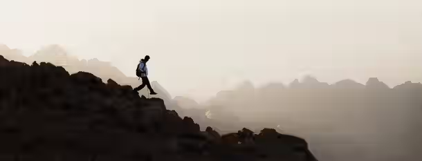 Ascending to Leadership: A Journey of Growth A lone hiker ascends a rugged mountain at dawn, symbolizing the challenging journey of personal growth and self-discovery.