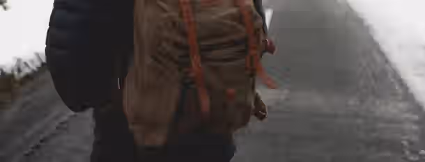 Path to Growth: An Emerging Leader's Journey A solitary figure with a backpack, symbolizing an emerging leader's journey towards self-improvement on a snowy path.