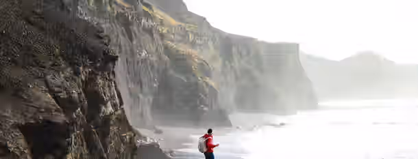 Forging Leadership on Misty Shores A lone hiker ventures along a rugged coast, symbolizing an emerging leader's journey towards self-improvement amidst challenges.