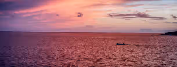 Charting the Path to Self-Discovery A lone boat sails towards the horizon under a vibrant sunset, symbolizing an emerging leader's journey to enlightenment and growth.