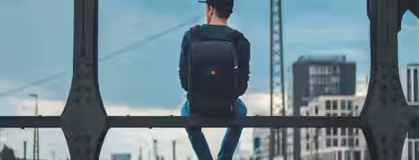 Reflecting on the Path to Personal Growth A young individual with a backpack sits on a bridge, gazing thoughtfully into a cityscape, embodying the journey of an emerging leader.
