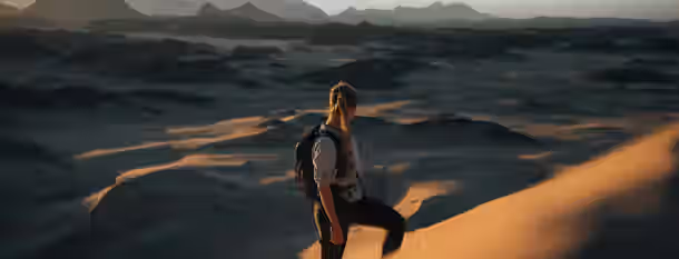 Scaling the Dunes: A Leader's Path to Enlightenment A solitary adventurer climbs a sunlit dune, symbolizing the arduous and rewarding journey of self-improvement and leadership.
