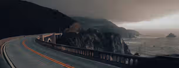 Curving Path to Leadership A winding road through rugged cliffs under a moody sky, symbolizing the journey of perseverance and growth for an emerging leader.
