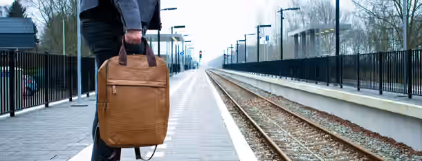 Embarking on a Path to Personal Growth Standing alone on a quiet platform, a person patiently waits, holding a backpack, symbolizing a new leader's journey to self-discovery.