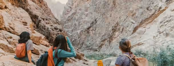 Ascending the Peaks of Potential Three adventurers gaze at a rugged canyon, embodying a leader's path of discovery and growth through life's challenges and opportunities.