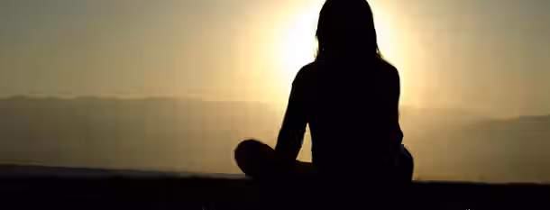 Sunrise of Self-Discovery for Emerging Leaders A contemplative figure meditates at sunrise, symbolizing an emerging leader's journey towards enlightenment and self-improvement.