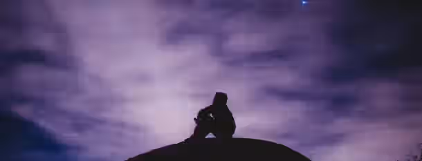 Contemplation Under the Twilight Sky Silhouette of a person sitting reflectively atop a hill under a vast, starry sky, symbolizing a leader's introspective journey to growth.