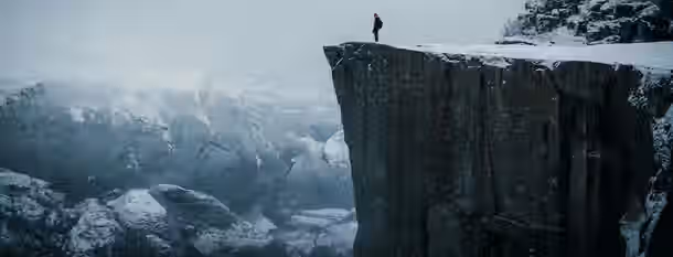 Standing on the Precipice of Leadership A lone figure stands at the edge of a towering cliff, symbolizing an emerging leader ready to embrace challenges and personal growth.