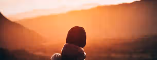 Embracing the Dawn of Leadership A lone figure gazes at a sunrise, symbolizing the start of an emerging leader's journey towards self-improvement and growth.