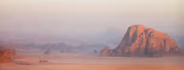Climbing Peaks: A Leader's Path to Self-Discovery Solitary, sunlit rock formation rises in a misty desert landscape, symbolizing the solitary yet illuminating journey of emerging leadership.