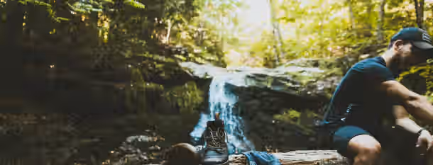 Trekking Toward Self-Discovery A climber rests by a waterfall, contemplating the transformative journey to personal growth and leadership amidst the wilderness.