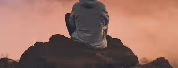 Reflection on the Summit of Self-Discovery A lone figure sits on a rugged mountain at dusk, symbolizing reflection and the dawn of personal growth on their leadership journey.