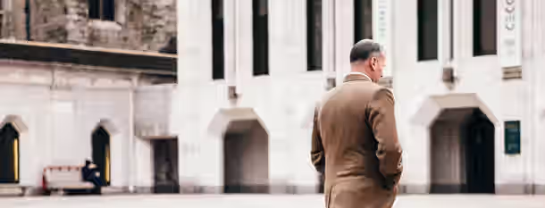 Steps Toward Leadership and Self-Growth A man in a suit walks purposefully towards a grand building, embodying the journey of an emerging leader's quest for self-growth.