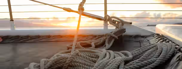Sailing Towards Personal Growth at Dawn A sailboat deck at sunrise, ropes neatly coiled, symbolizing an emerging leader's journey towards self-improvement and clarity.