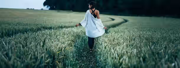Navigating Through Fields of Self-Discovery A woman walks through a vast field, symbolizing the journey of an emerging leader embracing growth and self-discovery.