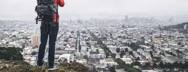 Scaling Heights: The Path to Leadership Growth An individual stands atop a hill, gazing over a vast cityscape, symbolizing an emerging leader's journey to newfound horizons of self-improvement.